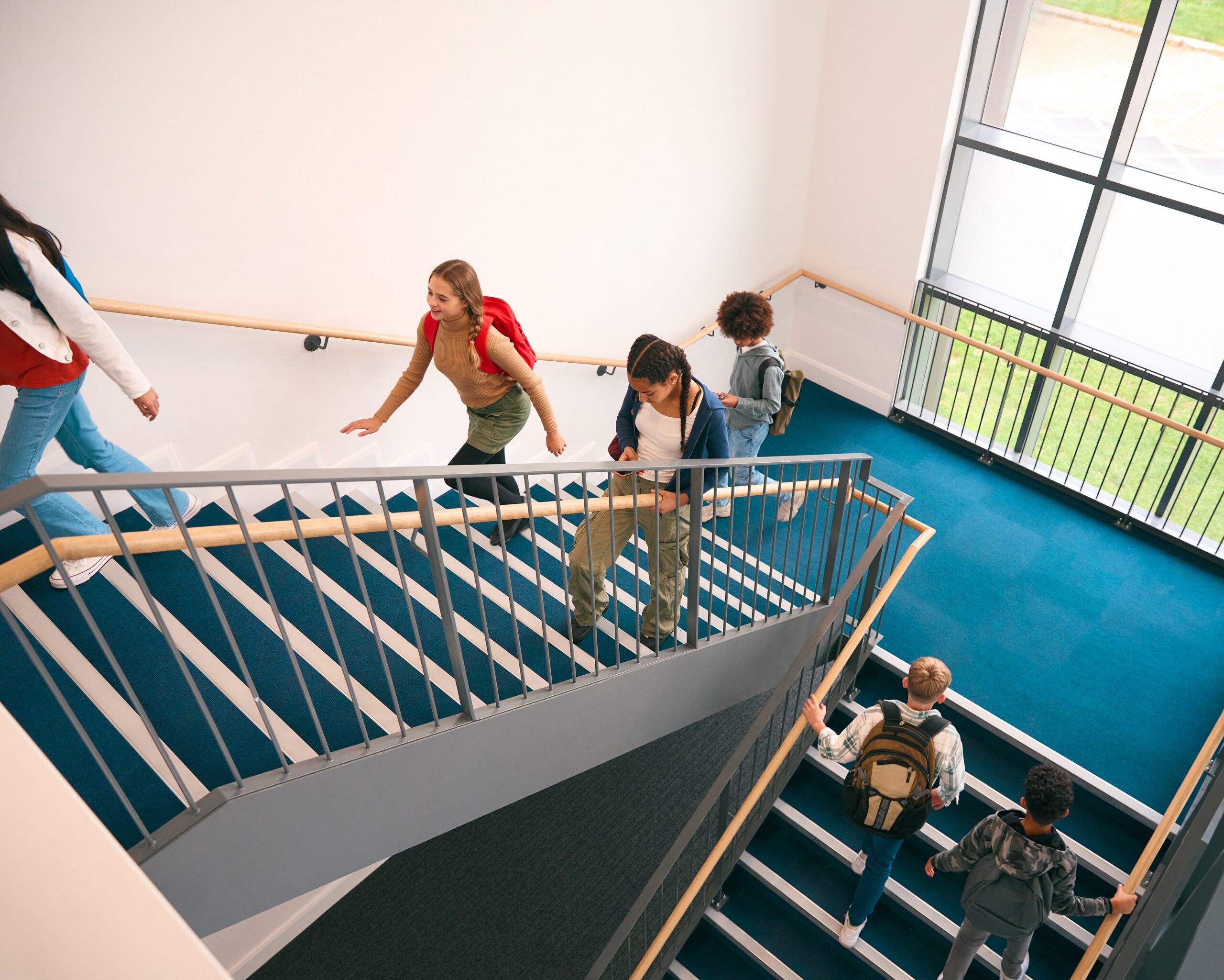 Group Of Secondary Or High School Pupils Inside School Building On Stairs Going To Lesson